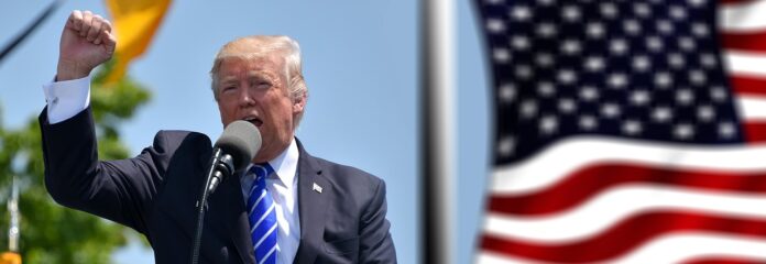 Donald Trump dando un discurso, con una bandera de Estados Unidos al fondo.