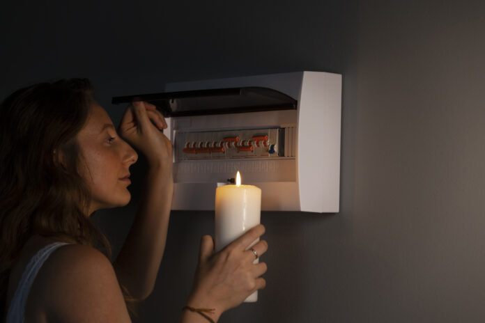 Mujer revisa interruptores eléctricos durante un apagón sosteniendo una vela