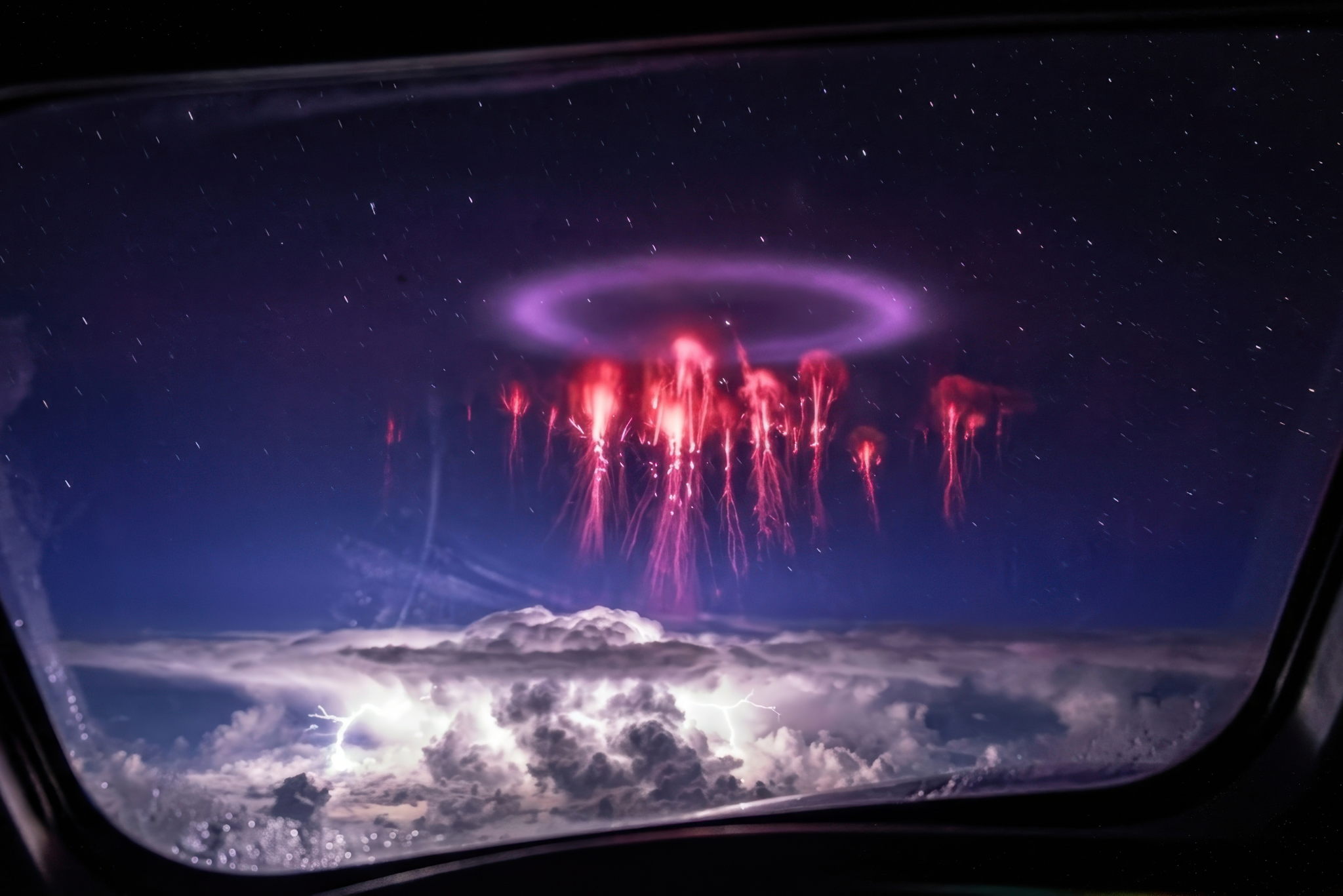 Red sprites and elve ring plasma discharge above thunderstorm captured from aircraft window — Earth's atmospheric electrical circuit visible